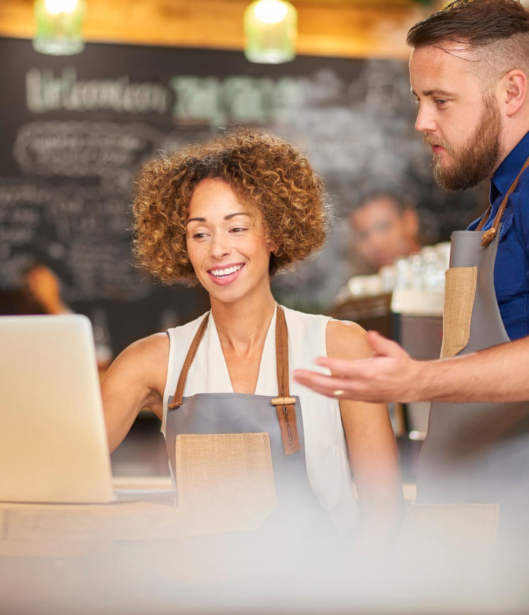 man and woman wearing apron in front of laptop